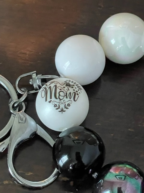 Close up. This bracelet features ten 20mm acrylic beads in black and white, with one hexagon black bead and one mom bead with a silver swivel large lobster clasp keyring.