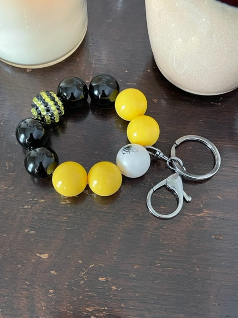 This bracelet features ten 20mm bubble gum beads with with two feature beads one yellow and black rhinestone bead and one with a bumble bee. The other 8 beads are 4 black and 4 yellow, with clasp is a silver swivel lobster clasp keyring.