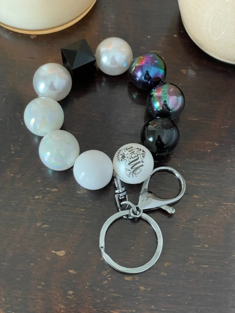 This bracelet features ten 20mm acrylic beads in black and white, with one hexagon black bead and one mom bead with a silver swivel large lobster clasp keyring. 